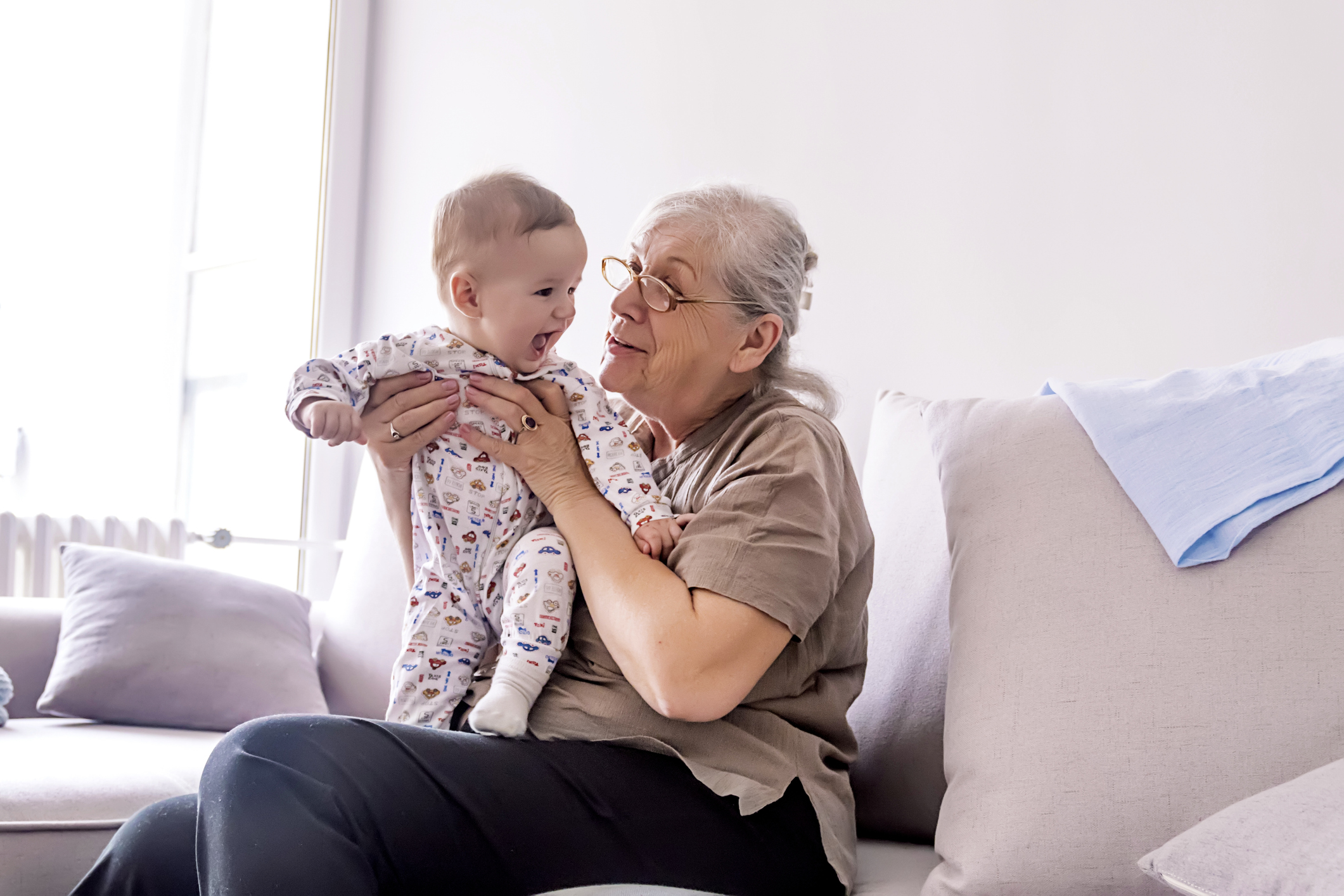 Multi generation family playtime Grandmother holding little grandson in the room at home. Senior woman hold little baby cute smiling. Happy grandmother with her grandchild in home.